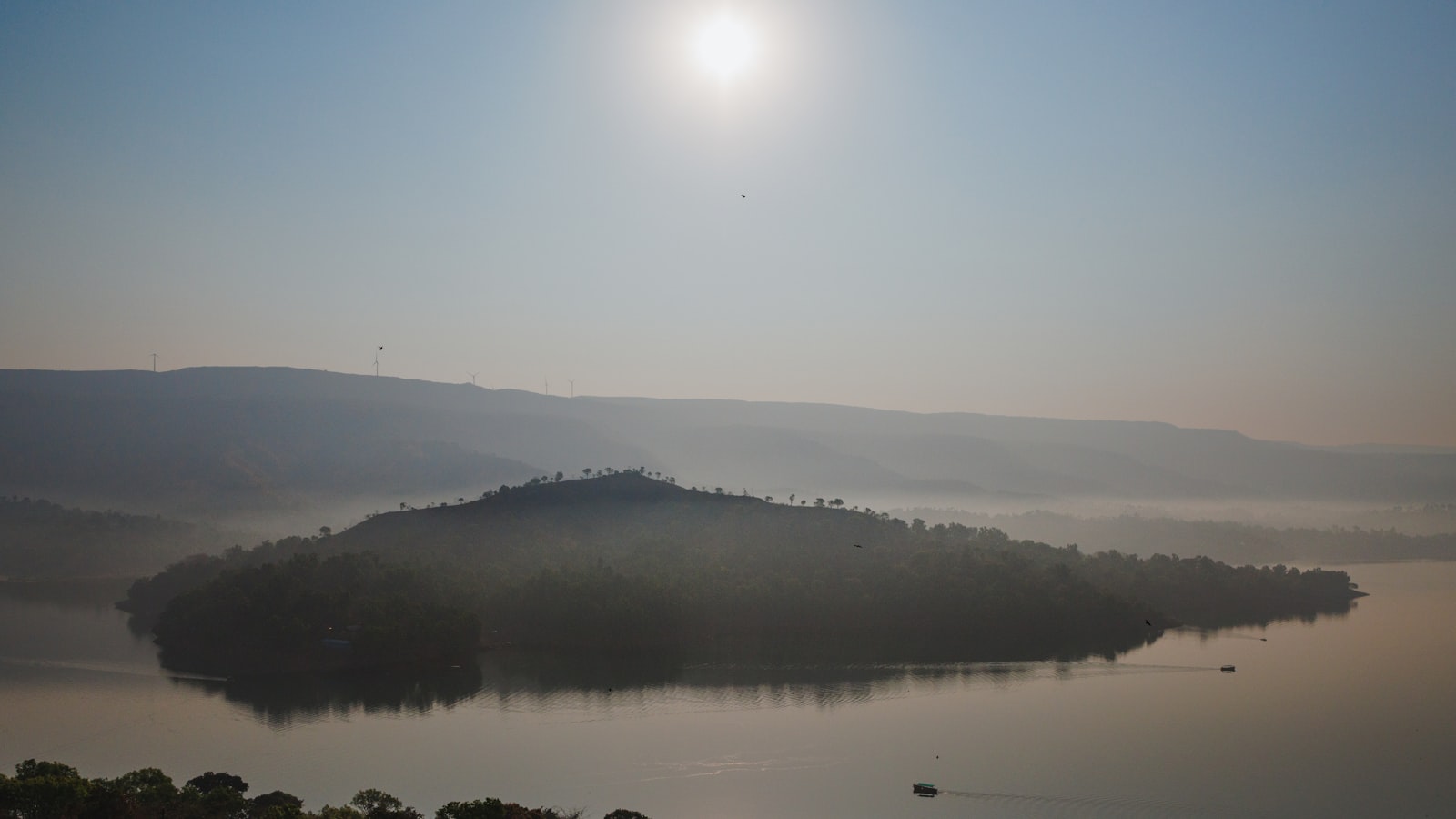 A still lake at golden hour with forested hills behind it