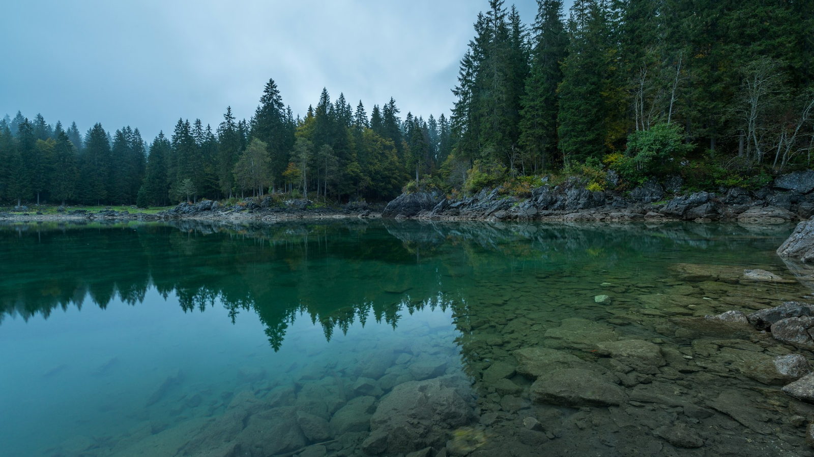 A still lake at dusk with the far shore going dark