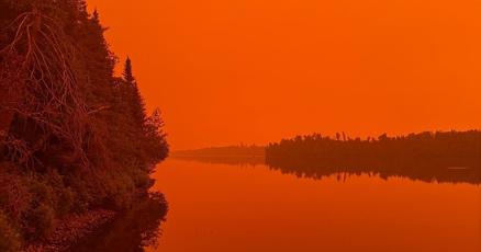 Wildfire smoke turning the sky orange over the Lake Superior shoreline, July 2026